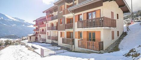 A multi-story hotel with balconies, located in a snowy mountainous area.