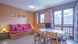 A cozy room with a wooden sofa, a dining table with chairs, and large windows offering a mountain view. - 10m from ski slopes, 1st floor, balcony, tv, 26m², Aussois (Aussois)