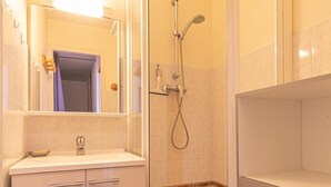 Une salle de bain avec une douche à parois de verre, un lavabo et un miroir.