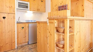 Une cuisine avec des meubles de rangement en bois, un four encastré et un îlot central doté d’étagères.