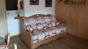 Puisesta sohvasta, jossa on topattu päällinen, ja huoneessa on puuseinät ja puulattia.