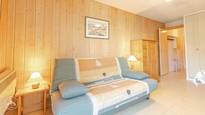 Ein gemütliches Schlafzimmer mit Holzwandverkleidung, einem Bett mit gestreifter Bettdecke, zwei Nachttischlampen und einem gerahmten Bild an der Wand.