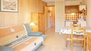 Ein gemütliches Wohnzimmer mit einer Couch, einem Esstisch mit Stühlen und einer Küchenzeile mit Schränken und Geräten.