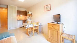 Ein kompakter Wohnbereich mit Essplatz, einer Küchenzeile, einem Fernseher und einem Kleiderschrank.