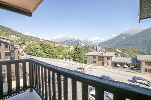 Un balcon donnant sur une route, des immeubles et des montagnes.