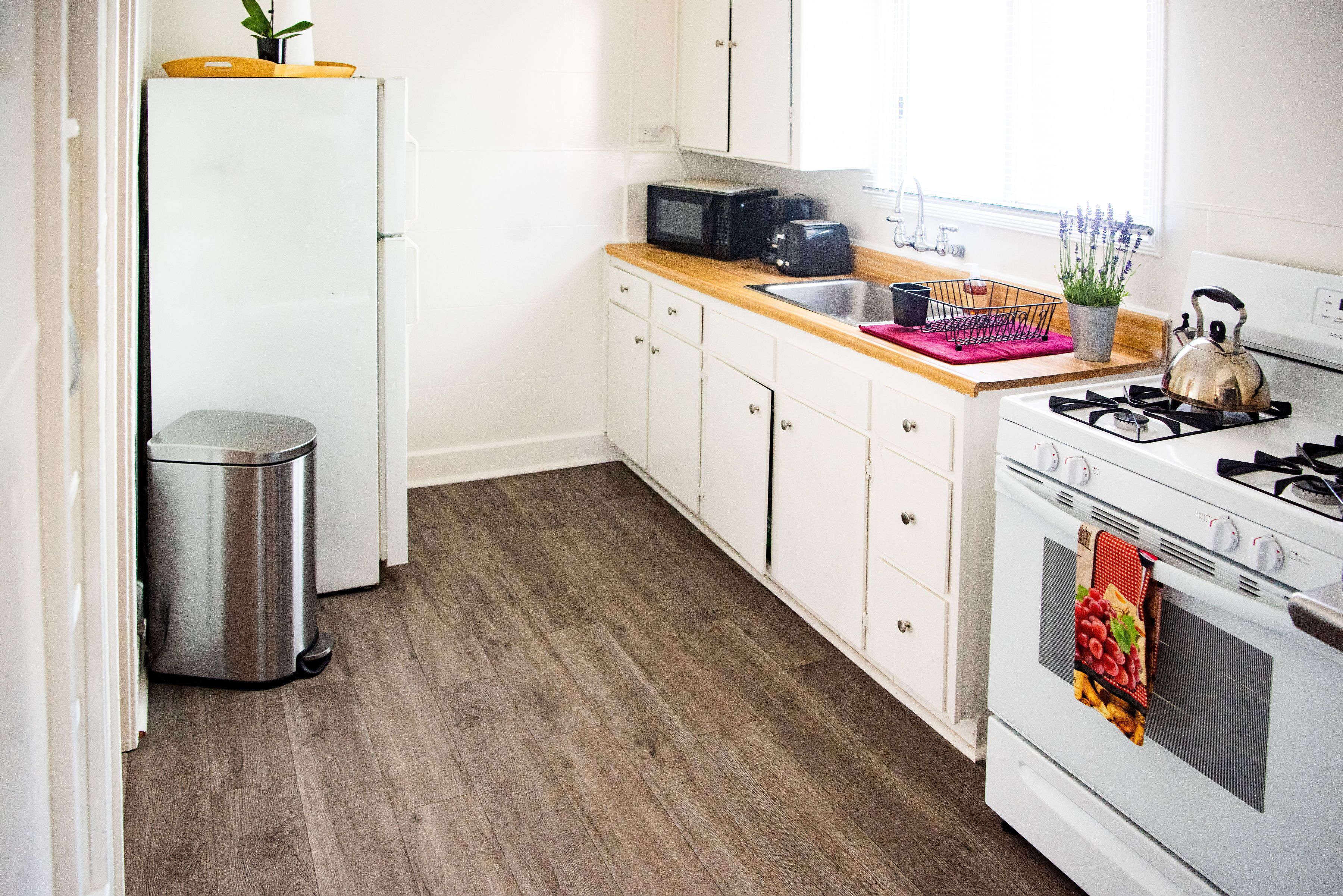 A compact kitchen with white cabinets, a microwave, a toaster, a sink, and a stove.