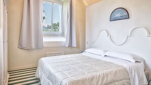 A bedroom with a bed, a window with curtains, a wall-mounted picture, and a radiator. - Villa La Pieve - an old church now turned into a welcoming and charming villa (Cortona)