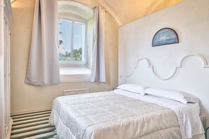 Ein Schlafzimmer mit Bett, einem Fenster mit Vorhängen, einem Wandbild und einer Heizung.