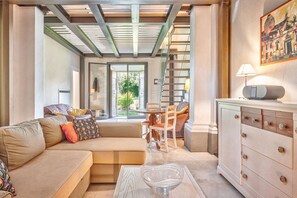 Ein modernes Wohnzimmer mit einer Couch, einem Glastisch, einem Schrank und einer Treppe, die in einen Außenbereich führt.