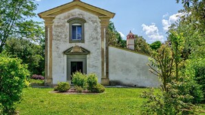A small, single-story building with a central entrance and a small tower in the background. - Villa La Pieve - an old church now turned into a welcoming and charming villa (Cortona)