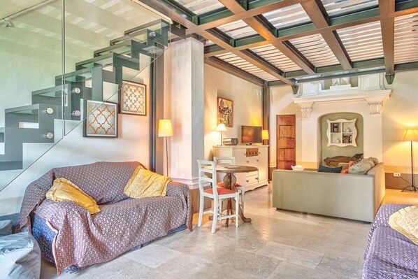 A modern interior with a staircase, a sofa, a dining table, and a fireplace.