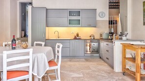 A compact kitchen with grey cabinets, a microwave, an oven, and a dining area with a table and chairs. - Villa La Pieve - an old church now turned into a welcoming and charming villa (Cortona)