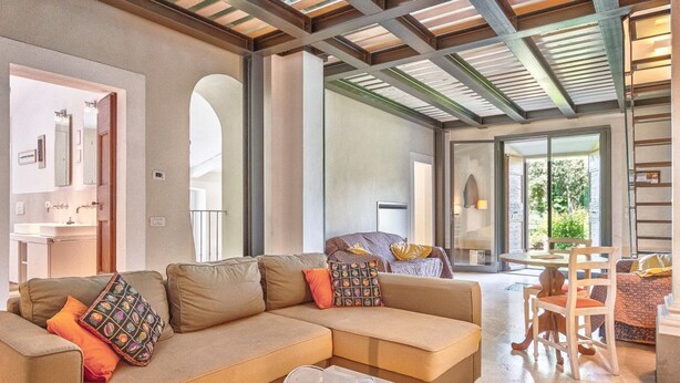 A modern living room with a sectional sofa, a coffee table, and a dining area with a table and chairs. - Villa La Pieve - an old church now turned into a welcoming and charming villa (Cortona)