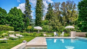 A swimming pool with lounge chairs and umbrellas, surrounded by greenery and trees. - Villa La Pieve - an old church now turned into a welcoming and charming villa (Cortona)