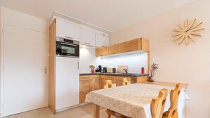 A compact kitchen with white cabinets, a built-in oven, and a dining area with a table and chairs. - 300m from ski slopes, 2nd floor, balcony, tv, ski locker, 41m², Aussois (Aussois)