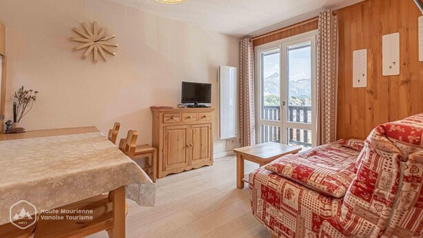 A cozy room with a wooden cabinet, a television, a dining table, and a patterned sofa. - 300m from ski slopes, 2nd floor, balcony, tv, ski locker, 41m², Aussois (Aussois)