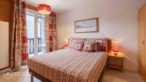 A bedroom with a bed, a nightstand, a lamp, a window with curtains, and a painting on the wall. - 300m from ski slopes, 2nd floor, balcony, tv, ski locker, 41m², Aussois (Aussois)