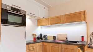 A compact kitchen with wooden cabinets, a built-in oven, and a coffee maker. - 300m from ski slopes, 2nd floor, balcony, tv, ski locker, 41m², Aussois (Aussois)