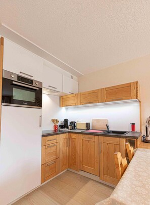 A compact kitchen with wooden cabinets, a built-in oven, and a coffee maker. - 300m from ski slopes, 2nd floor, balcony, tv, ski locker, 41m², Aussois (Aussois)