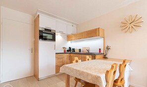 A compact kitchen with white cabinets, a built-in oven, and a dining area with a table and chairs. - 300m from ski slopes, 2nd floor, balcony, tv, ski locker, 41m², Aussois (Aussois)