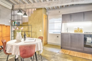 A modern kitchen with grey cabinets, a built-in oven, and a dining area with a round table and chairs.