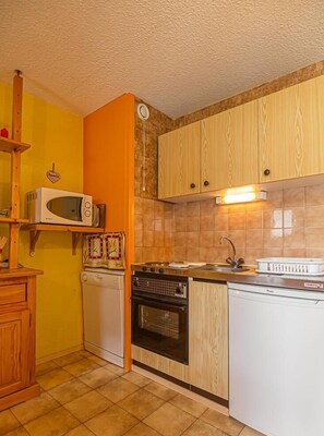 Compact kitchen with modern design, microwave, dishwasher, and oven.