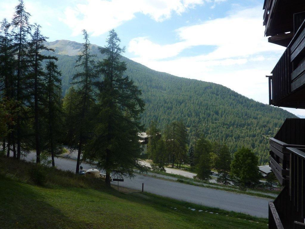 A view of a mountain with a road leading to a building with a balcony.