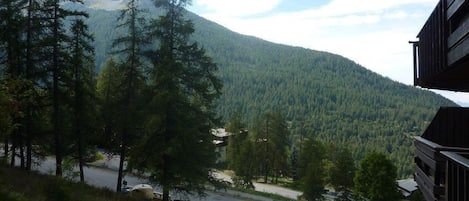 A view of a mountain with a road leading to a building with a balcony.