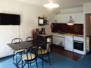 A compact kitchen with a dining table and chairs, a microwave, a stove, and a sink.