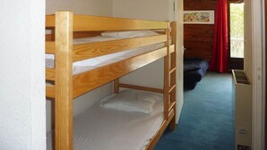 A bunk bed in a room with a blue carpet, a wooden door, and a red curtain. - 300m from ski slopes, 2nd floor, view forest, balcony, tv, ski locker, 24m², Les Orres (Les Orres)