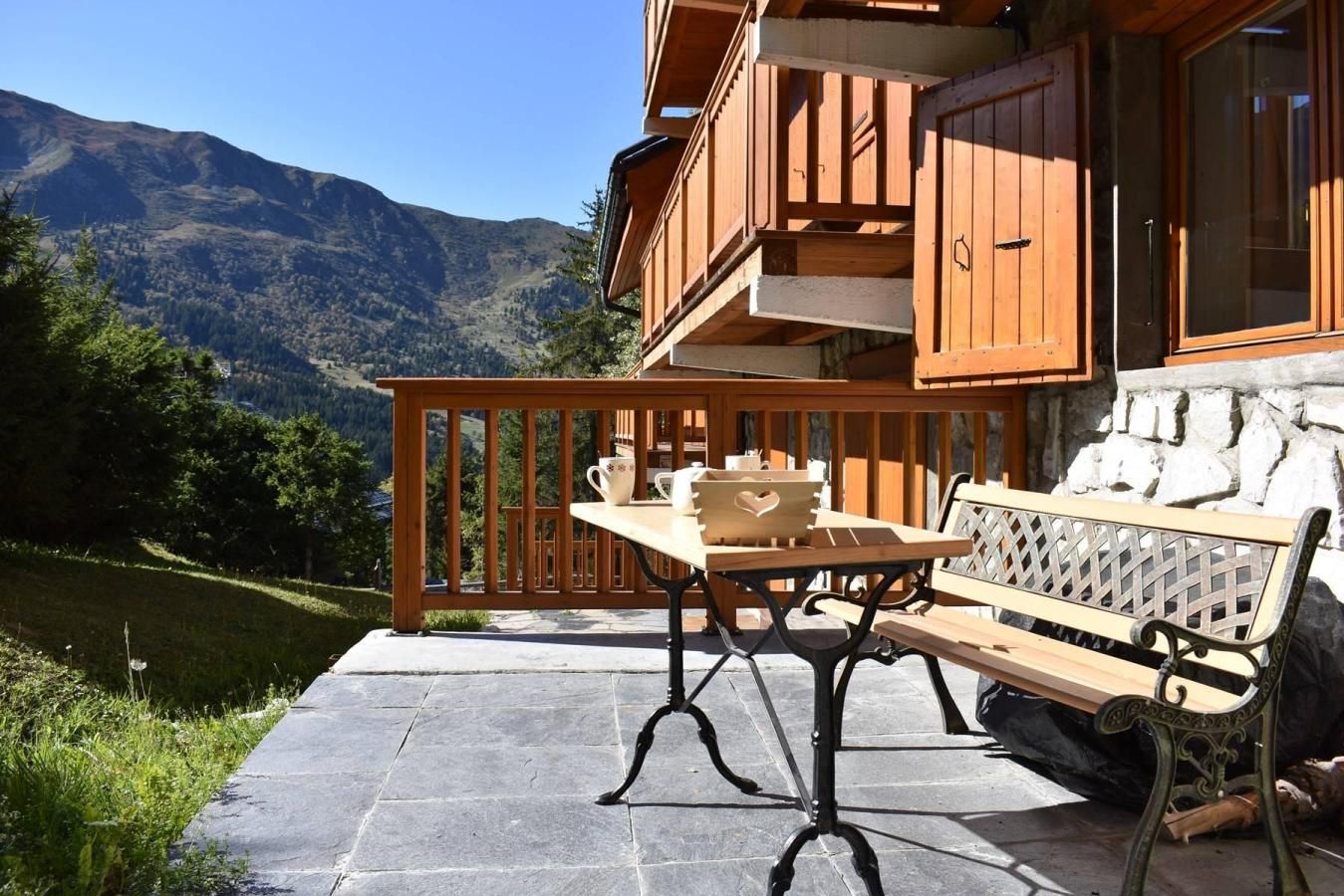 A wooden deck with a table and bench, overlooking a mountainous landscape.