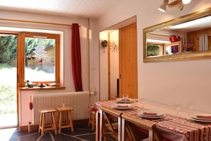 A dining area with a table set for four, a window with a view of greenery, and a mirror on the wall.
