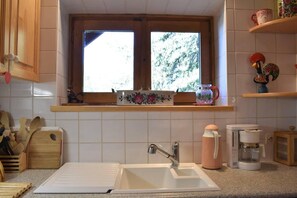 A kitchen with a window, a sink, a coffee maker, and wooden utensils. - 250m from ski slopes, Ground floor, terrace, fireplace or stove, tv, ski locker, 50m², Méribel (Méribel - Les Allues)