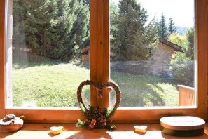 A window with a heart-shaped wreath and a small Christmas tree decoration.
