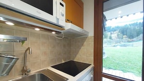 A kitchen with a stainless steel sink, a black induction cooktop, and wooden cabinets. - View ski slopes, terrace, tv, ski locker, 42m², Valmorel (Valmorel)