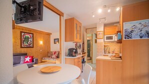 A compact living space with a dining area, kitchenette, and a sofa with a star pillow. - View ski slopes, terrace, tv, ski locker, 42m², Valmorel (Valmorel)