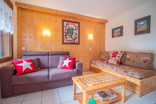 Een gezellige woonkamer met een houten wand, een bank, een divan en een salontafel.