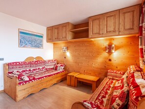 A cozy room with a wooden sofa and bench, wooden cabinets, and a framed picture on the wall.