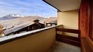 Un balcon doté d’une balustrade en bois, d’où l’on peut admirer un paysage montagneux.