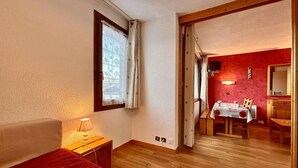 Une chambre à coucher avec un lit, une lampe de chevet et une vue sur un coin repas comprenant une table et des chaises.