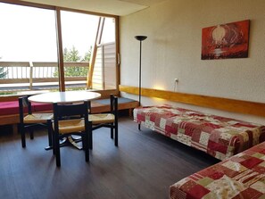 Een kamer met een ronde tafel, twee stoelen, een bank en een schilderij aan de muur.