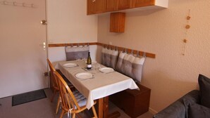 Un coin repas avec une table dressée pour quatre personnes, des placards en bois au-dessus et un banc rembourré le long du mur.