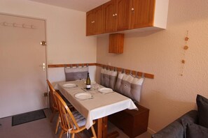 Ein Essbereich mit einem Tisch für vier Personen, Holzschränken darüber und einer gepolsterten Bank an der Wand.