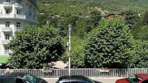 A multi-story building with balconies, surrounded by lush greenery and mountains in the background. - 150m from resort center, 1st floor, balcony, tv, 26m², Brides Les Bains (Brides-les-Bains)