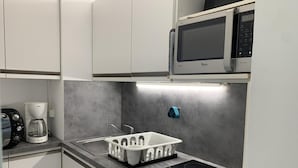 A modern kitchen with white cabinets, a microwave, a coffee maker, and a built-in oven. - 150m from resort center, 1st floor, balcony, tv, 26m², Brides Les Bains (Brides-les-Bains)