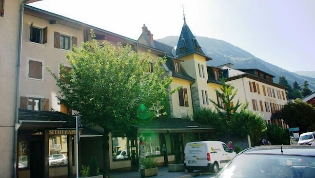 A street view with a row of buildings, including a hotel with a visible sign. - 150m from resort center, 1st floor, balcony, tv, 26m², Brides Les Bains (Brides-les-Bains)