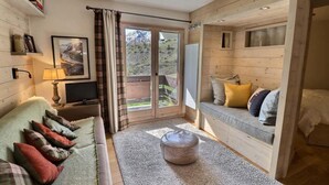 A cozy room with a sofa, a television, and a window with curtains. - 10m from ski slopes, 1st floor, view ski slopes, balcony, 40m², Méribel-Mottaret (Méribel - Les Allues)