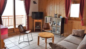 A cozy cabin interior with a wooden floor, a sofa, two chairs, a television, and a cabinet with glass doors. - 1st floor, terrace, tv, ski locker, 61m², Pralognan-la-Vanoise (Pralognan-la-Vanoise)
