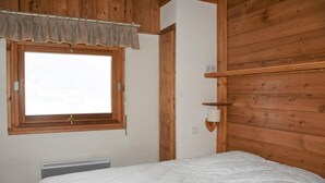 A bedroom with a wooden ceiling, a window with a curtain, a bedside lamp, and a bed with a white duvet. - 1st floor, terrace, tv, ski locker, 61m², Pralognan-la-Vanoise (Pralognan-la-Vanoise)