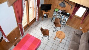 A cozy room with a sofa, a table with a striped tablecloth, two chairs, a television, and a cabinet with dishes. - 1st floor, terrace, tv, ski locker, 61m², Pralognan-la-Vanoise (Pralognan-la-Vanoise)